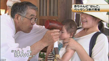 赤ちゃんのおでこにはんこを押す「元気に大きくなって」